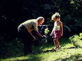 Grandfather with grandaughter planting a small tree