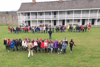Two groups of people standing outside one of teh buildings ar Fort Frederick.
